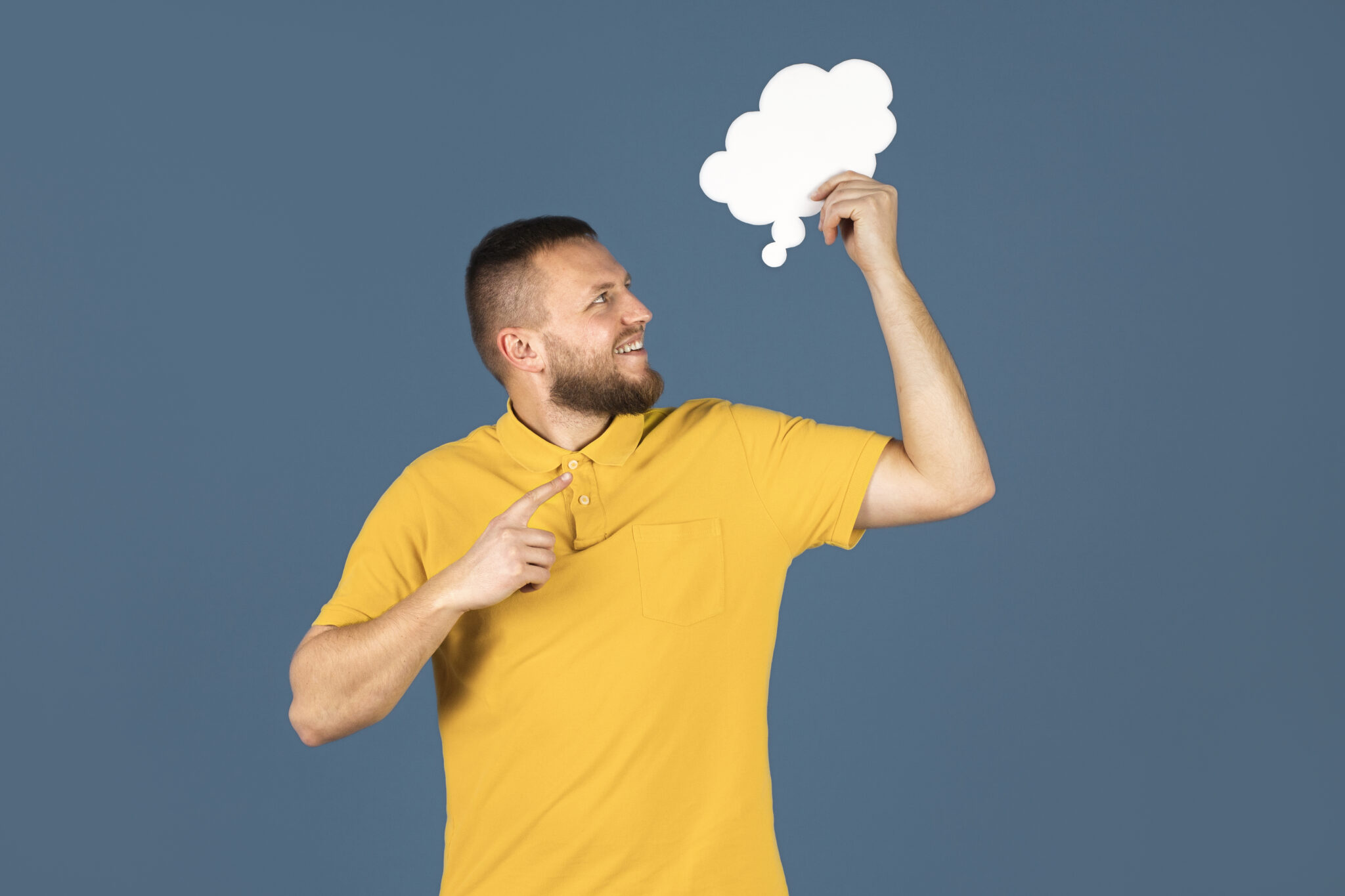 Uśmiechnięty mężczyzna w żółtej koszulce trzyma chmurkę i zastanawia się, co to jest ADHD.
