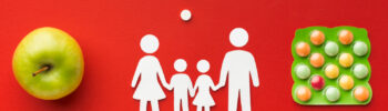 Terapia ADHD bez leków. Na czerwonym tle jabłko, grafika rodziny, rozsypane tabletki.